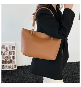 Detailed side view of brown leather tote bag with slim shoulder straps and gold hardware