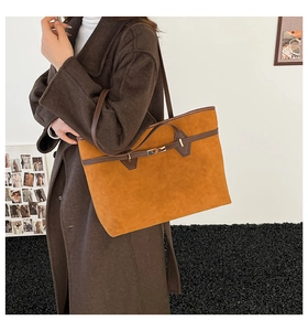 Détail du sac cabas en suède avec garniture en cuir marron et boucle dorée sur un modèle