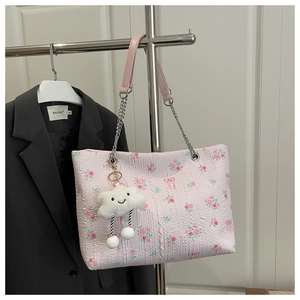 Close-up of pink floral tote bag with silver chain strap and cloud plush charm detail