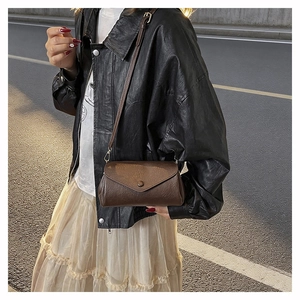 Close-up of vintage brown crossbody bag with lychee texture and round snap button