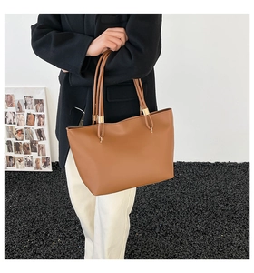 Caramel brown leather tote bag with gold metal rings shown on a shoulder for daily commute