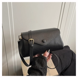 Detail of a vintage black textured crossbody bag with envelope flap and buckle
