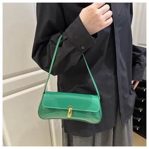 Detail of glossy green patent leather baguette bag featuring a gold twist-lock fastener