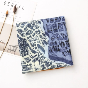 Gros plan d'un foulard en soie plié avec imprimé carte vintage sur une table épurée