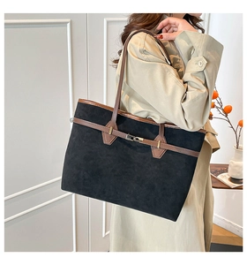 Détail du grand sac cabas en daim noir avec anses en cuir marron porté par un mannequin