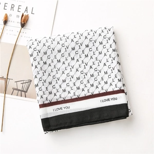 Détail de l'écharpe en coton et lin avec motif lettres et bordure à rayures