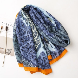 Détail d'un foulard en soie bleue avec imprimés d'architecture urbaine et bordure orange