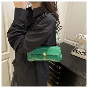 Close-up of green patent leather shoulder bag featuring a prominent gold U-shaped metal buckle