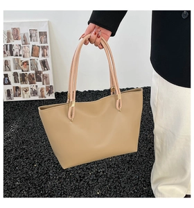 Detail of a large apricot tote bag with leather texture and elegant gold buckle accents