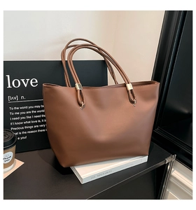Macro detail of brown tote bag with matte texture and minimalist gold metal hardware