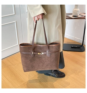 Gros plan d'un sac cabas en daim marron foncé avec lanière en cuir et boucle métallique