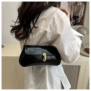 Close-up of black patent leather underarm bag with elegant gold metal oval lock