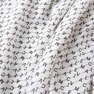 Détail du tissu de l'écharpe en mousseline blanche avec imprimé de lettres noires