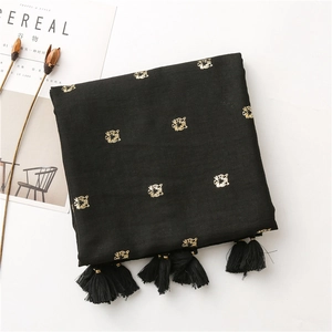 Detailed shot of a black cotton scarf featuring golden tiger head embroidery and tassels