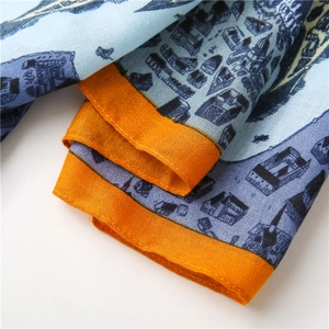 Détail du tissu bleu imprimé avec motifs de carte urbaine et bordure orange vif sur l'écharpe