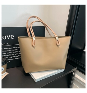 Detail of khaki tote bag featuring dual handles and golden metallic ring fasteners