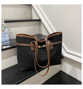Détail d'un grand sac cabas en daim noir avec anses en cuir marron sur des escaliers