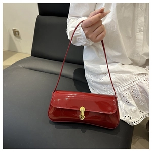 Detail of red patent leather baguette bag featuring a vintage gold metal lock buckle
