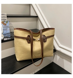 Gros plan d'un sac cabas en daim beige avec des lanières en cuir marron foncé sur bois