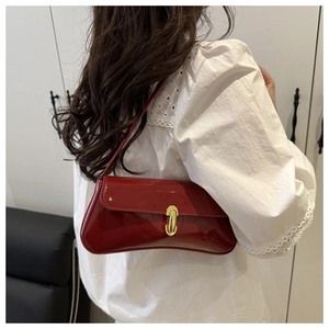 Close-up of burgundy patent leather baguette bag featuring a gold U-shaped metal buckle