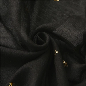Detailed close-up of golden bee foil print on soft black fabric scarf texture