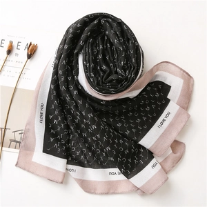 Détail d'une écharpe rose et noire avec imprimé lettres et bordure I LOVE YOU chic