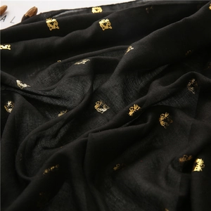 Macro shot of black cotton-linen scarf with golden tiger head foil print and fabric texture