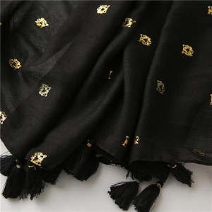 Detailed view of black scarf with golden tiger head prints and fringe tassel trim