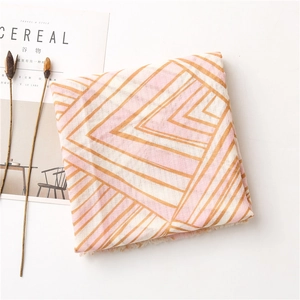 Detail view of cotton linen scarf with geometric pink and khaki patterns and fringe trim