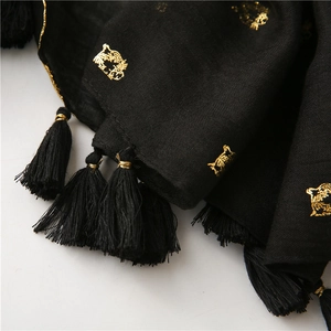 Detail of black cotton scarf with golden tiger head print and elegant fringe tassels
