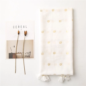 Detail of white scarf with gold tiger head prints and dense tassels on minimalist background