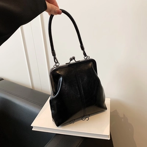Retro black patent leather handbag with metal clasp for a trendy minimalist look