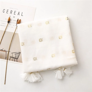 Detail of tiger head gold foil print and cotton tassels on a beige minimalist scarf