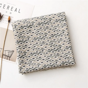 Detail view of wavy pattern and polka dots on linen-feel scarf with fringe edges