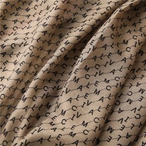 Détail macro du tissu d'écharpe beige avec imprimé de lettres noires et texture