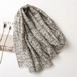 Linen feel scarf with wavy eye prints, styled with a magazine for a minimalist aesthetic