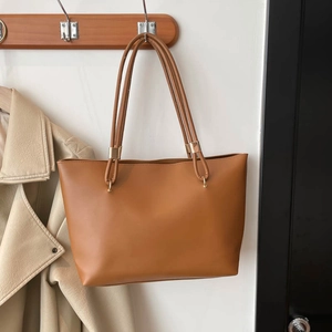 Minimalist tan leather tote bag with dual shoulder straps and gold metal hardware