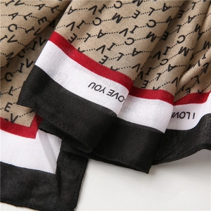 Détail de l'écharpe beige avec lettres noires et bordure rayée I LOVE YOU