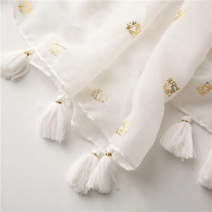 Detail of gold tiger head foil print and white fringe tassels on cotton linen scarf