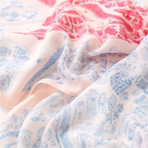Détail d'un foulard en soie imprimé avec motifs architecturaux rouges et bleus sur fond rose