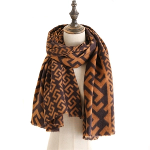 Detail of geometric monogram pattern and tassel fringe on cashmere-like shawl scarf