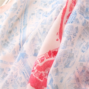 Gros plan détaillé de l'écharpe en soie rose clair avec motifs d'architecture européenne