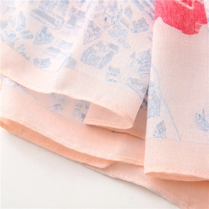 Gros plan détaillé d'une écharpe longue rose clair montrant la texture et les motifs