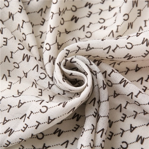 Détail macro d'une écharpe en coton beige avec des motifs de lettres noires modernes