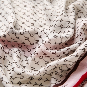 Gros plan sur l'écharpe en coton et lin montrant la texture douce et les lettres noires