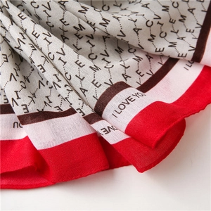 Vue détaillée du tissu léger de l'écharpe en coton avec bordure rouge et motifs lettres