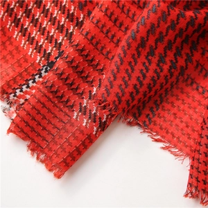 Vista macro dello scialle pied-de-poule rosso con trama cotone-lino e bordi sfrangiati
