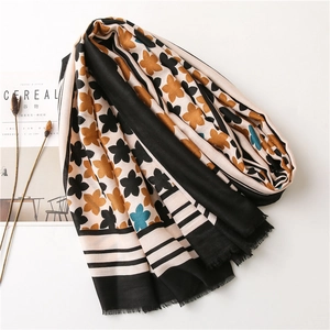 Floral cotton linen scarf with beige and orange stripes and frayed edges on a magazine