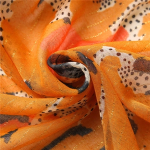 Detail of vibrant orange scarf with golden metallic lurex threads and polka dot patterns