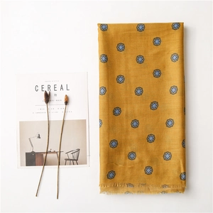 Detail of yellow cotton linen scarf with floral print and frayed fringe edges